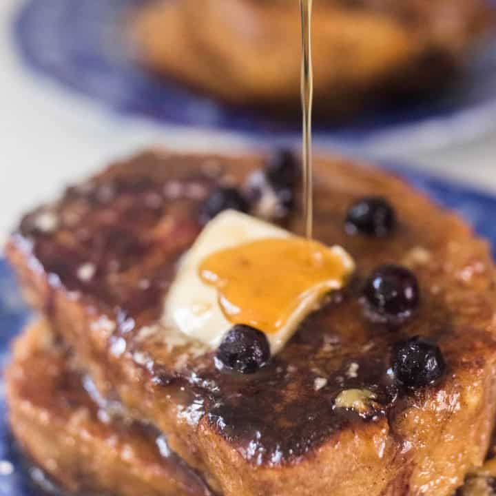 maple syrup being poured over sourdough French toast with blueberries