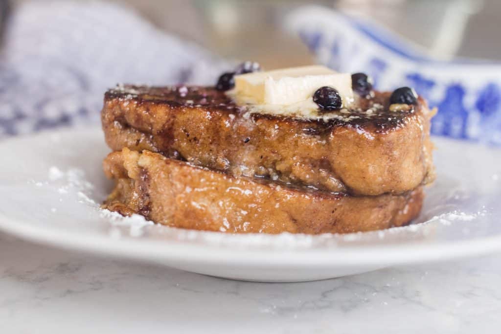 side view of two slices of sourdough French toast on a white plate