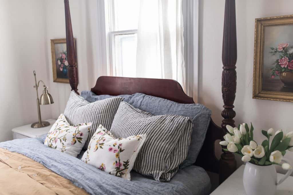 close up of beautiful linen and floral pillows on a wooden headboard. 