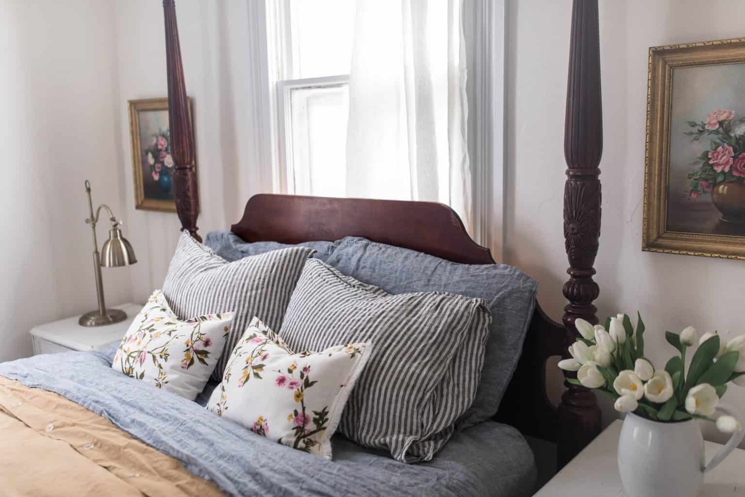 close up of beautiful linen and floral pillows on a wooden headboard.