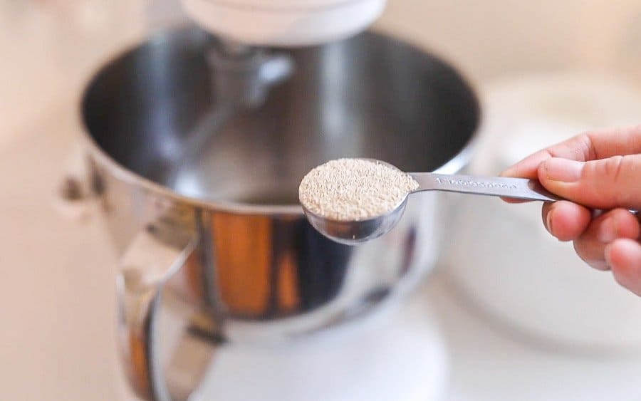 adding yeast to a stand mixer bowl with warm water