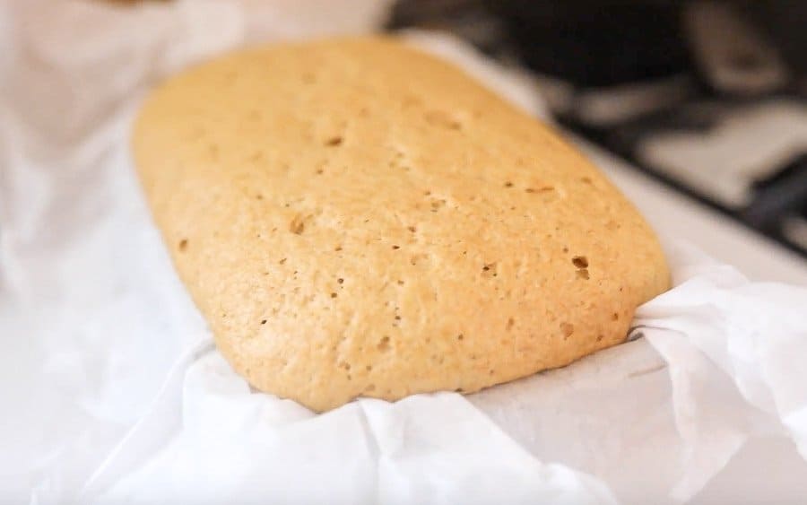 einkorn bread rising in a loaf pan lined with parchment