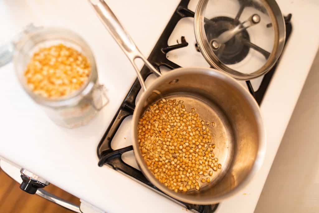 popcorn kernels in a stainless steel pot with oil