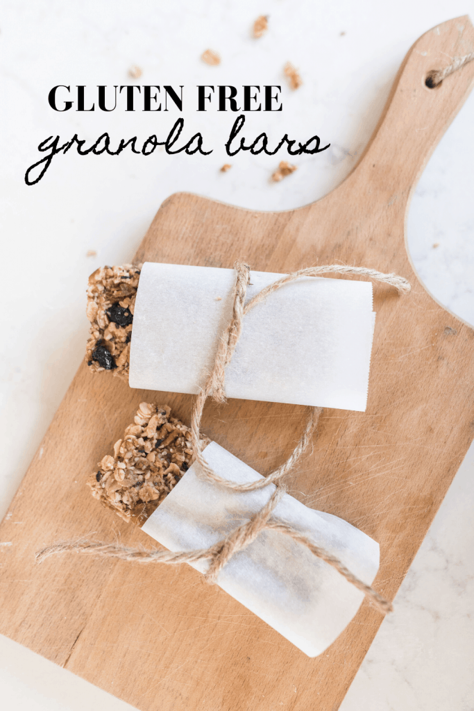 two homemade granola bars wrapped in parchment paper and tied with twine on a wood cutting bar