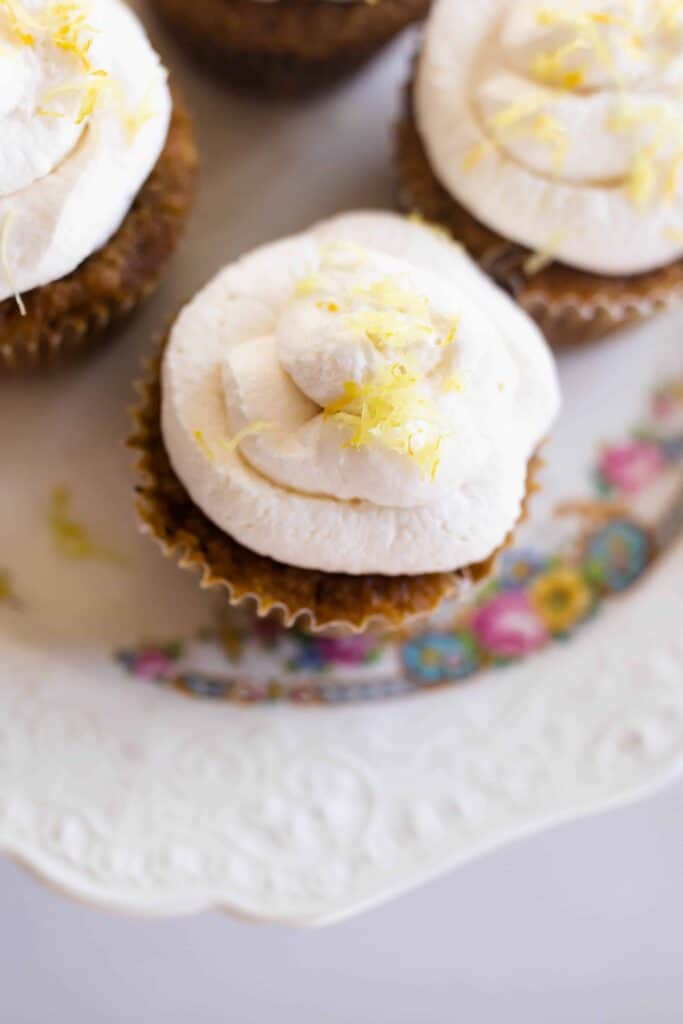 overhead shot of muffins with lemon whipped cream frosting topped with lemon zest.