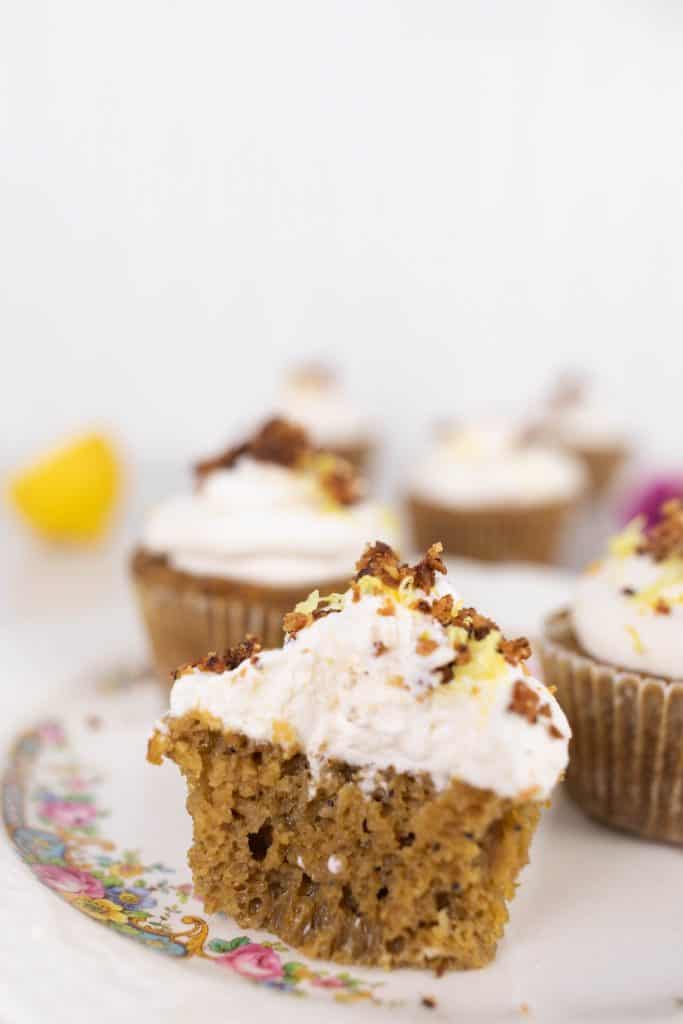 a muffin with frosting cut in half on antique plate