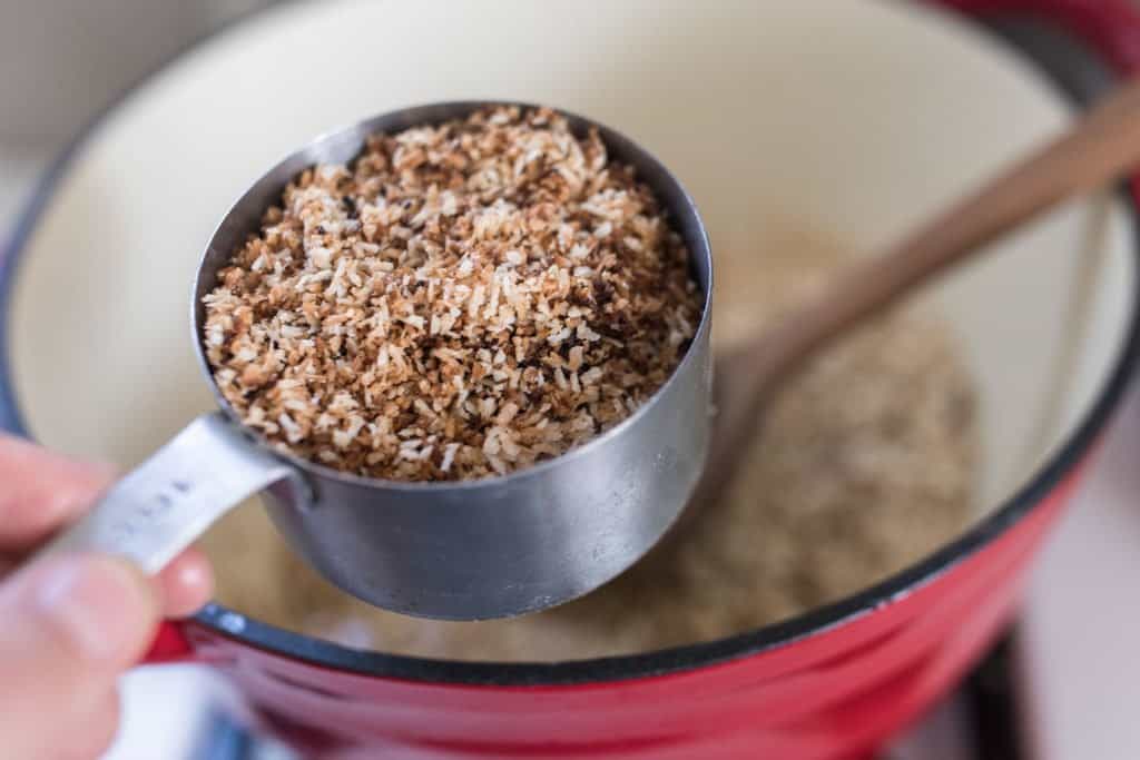 toasted coconut in a cup measuring cup over pot.