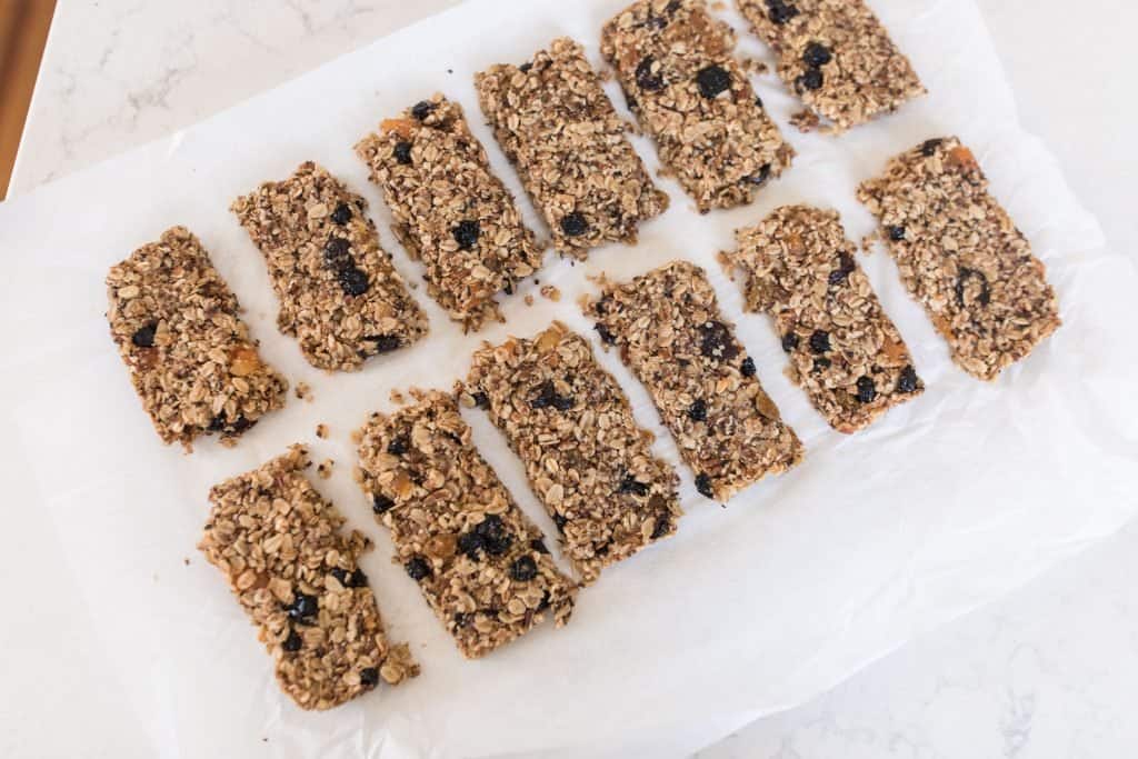 granola cut into 12 even bars on parchment paper.