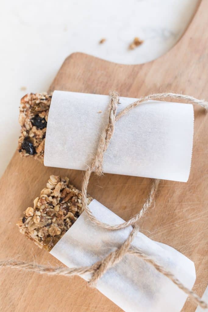 rustic granola bars wrapped in parchment paper and tied with twine on a cutting board