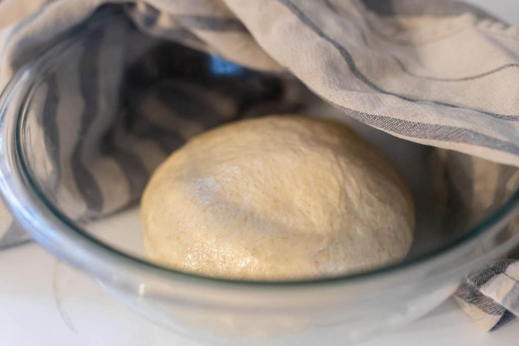 dough in a greased bowl with a towel over half the bowl before allowing it to ferment.