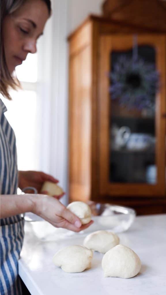 women placing sourdough dinner roll dough onto a quartz countertop