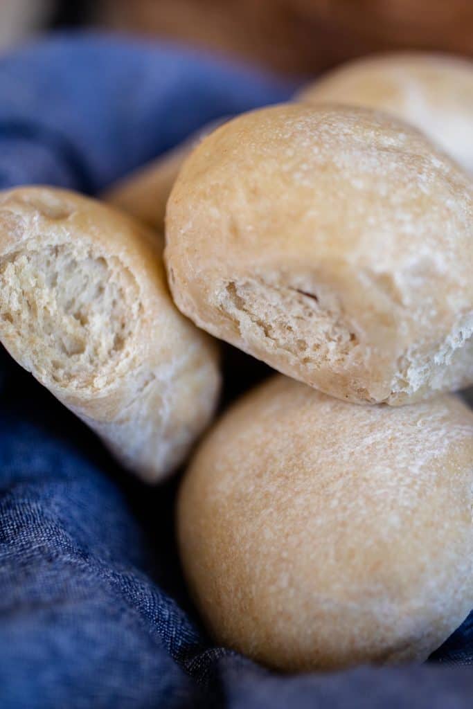 sourdough diner rolls stacked in a blue towel lining a basket