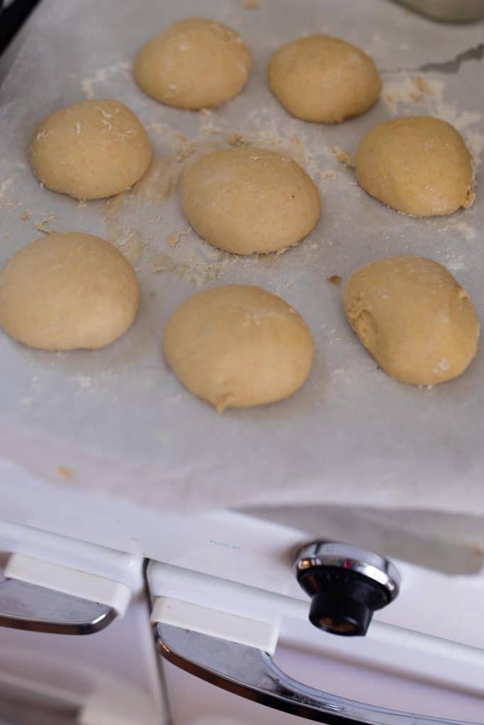 sourdough buns on parchment paper rising