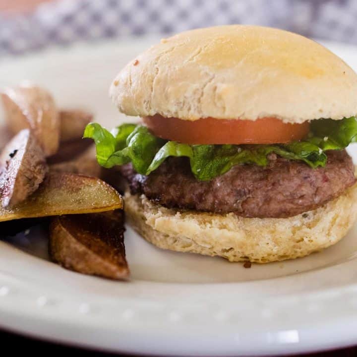 hamburger tomato and lettuce on a homemade sourdough bun on a white plate