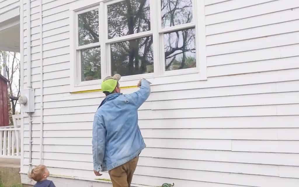 man measuring a window including the trim to make a diy window box