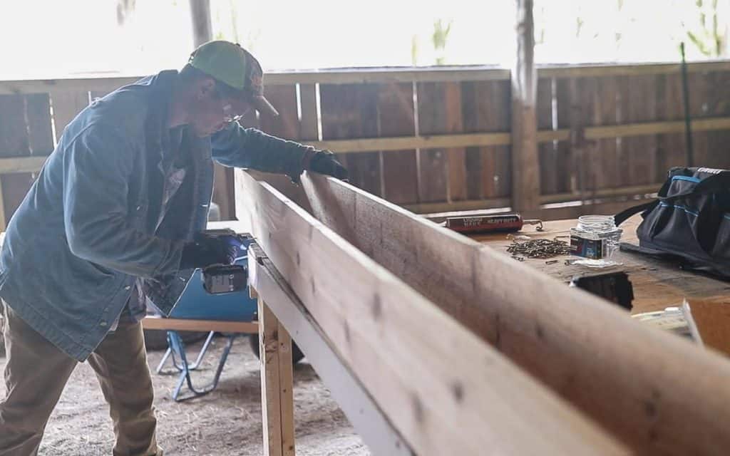 man drilling a 1x8 board onto another board to create DIY window box