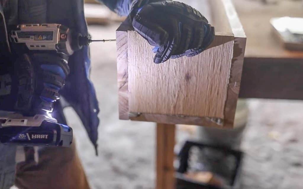 man drilling a end piece to a wooden flower box