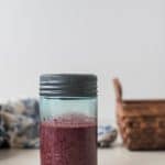 Fermented Blueberry Balsamic Dressing in a glass jar with a tin lid, basic and towel in the background