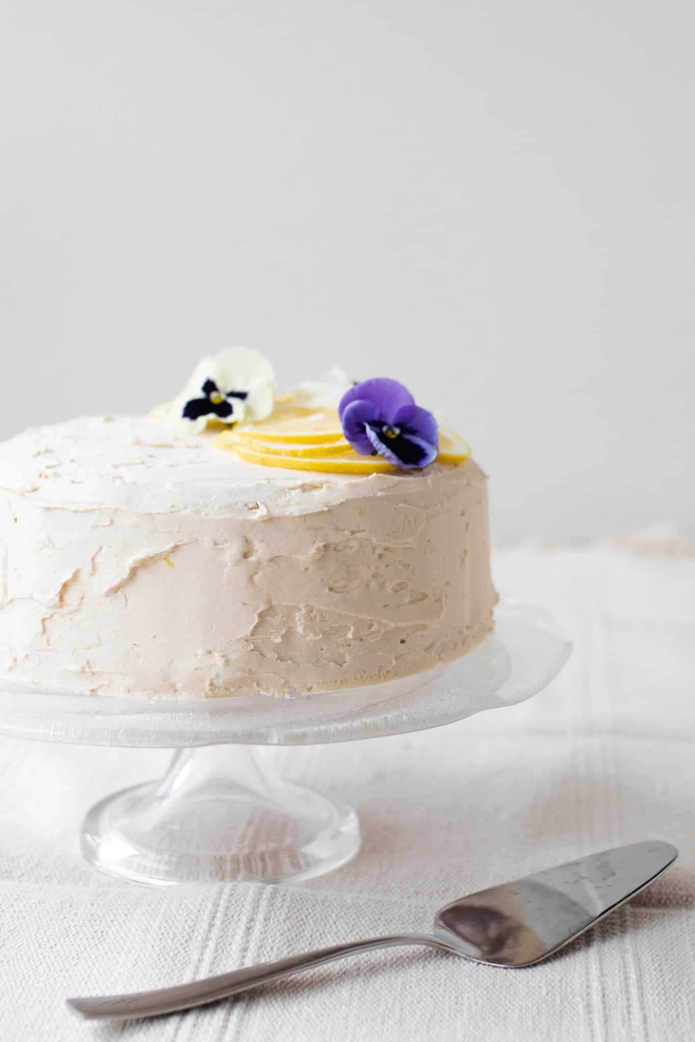 gluten free lemon cake with lemon icing topped with Leons and edible flowers.