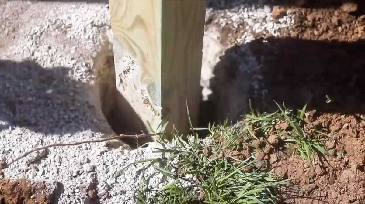 fence post in a hole with screening rock around