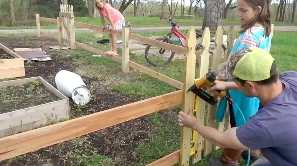 man using a brad nailer to nail pickets to stringers