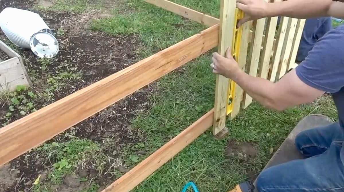 man placing pickets 2.5 inches apart using a level
