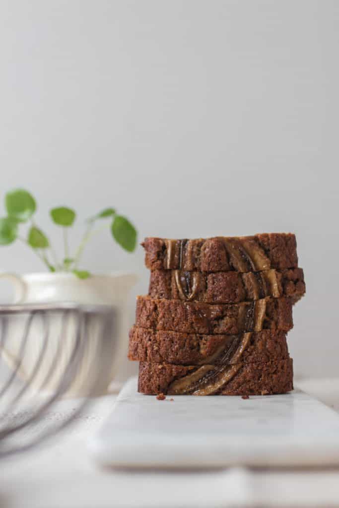 5 slices of sourdough banana bread on a marble cutting board with a plant in the background