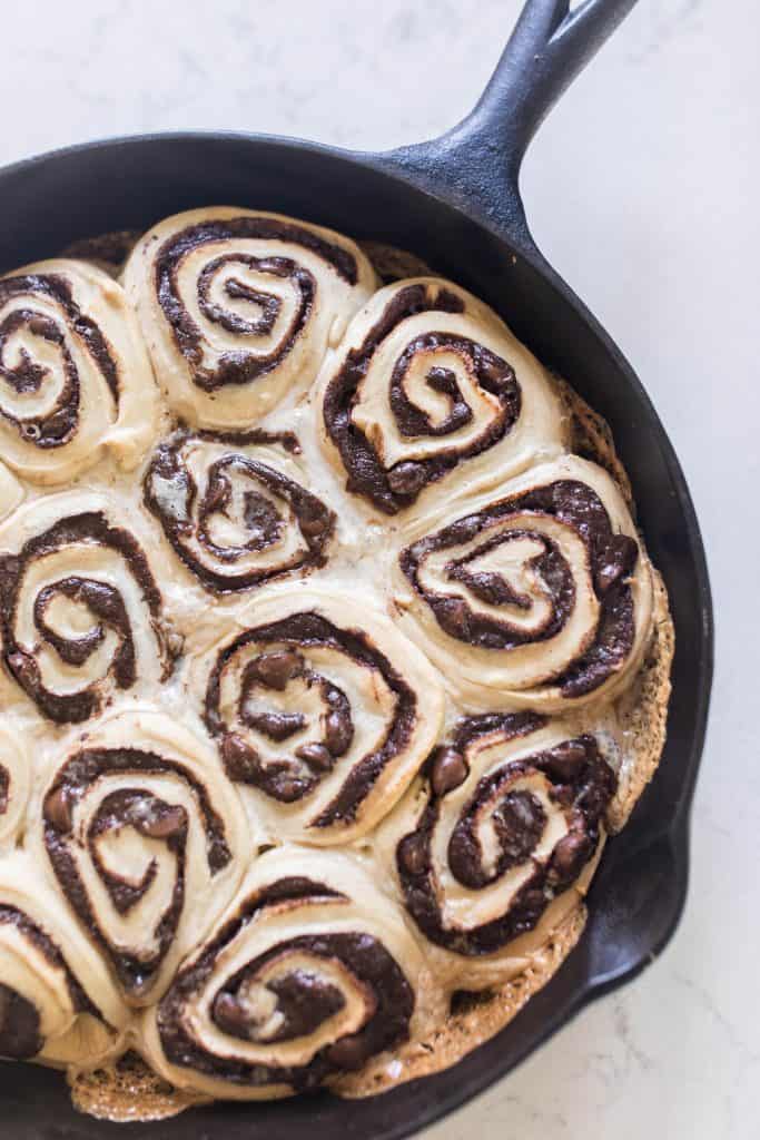 sourdough chocolate rolls with gooey swirled chocolate filling in a cast iron skillet on a white quarts countertop