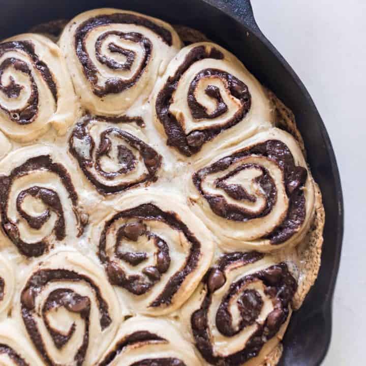sourdough chocolate rolls with gooey swirled chocolate filling in a cast iron skillet on a white quarts countertop