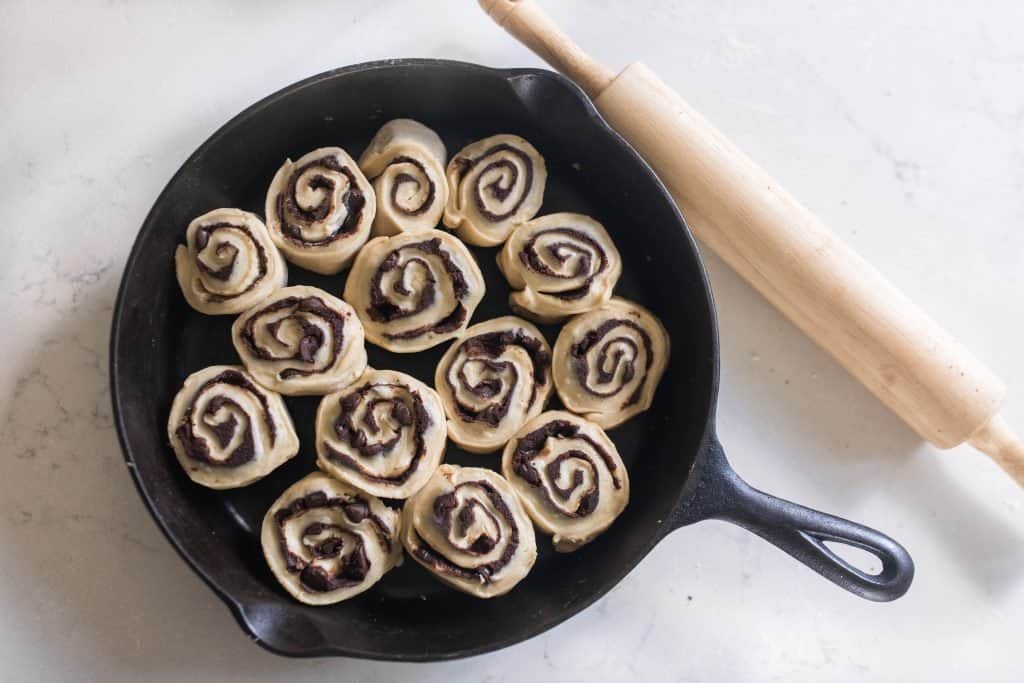 raw sourdough chocolate rolls in a cast iron skillet ready to be baked