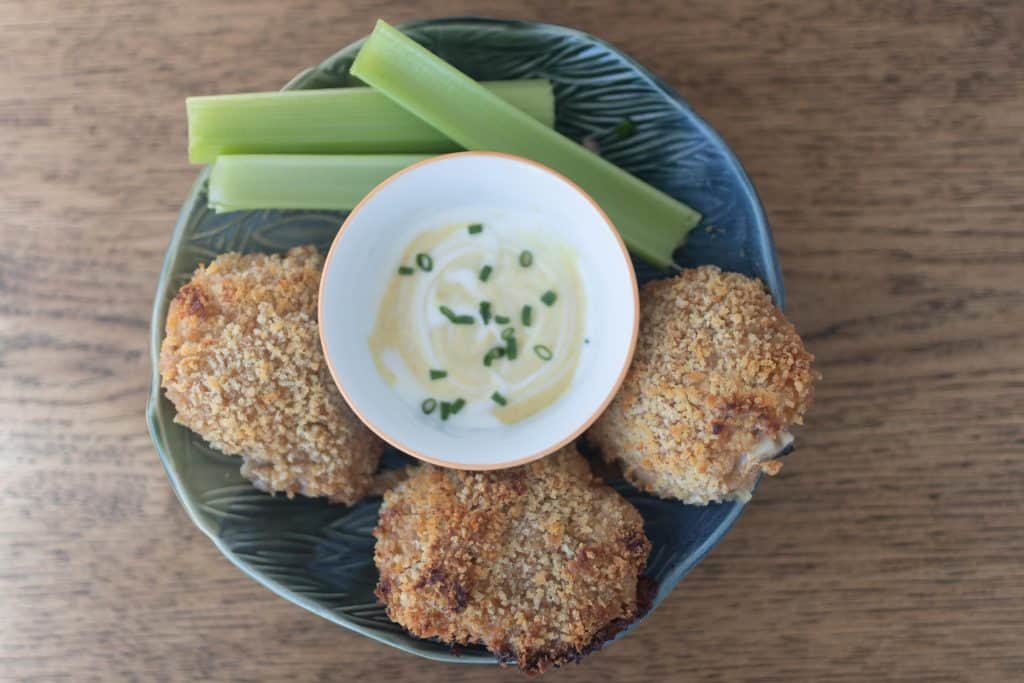 sourdough oven fried chicken in a blue bowl with celery and dipping sauce in the middle in a bowl