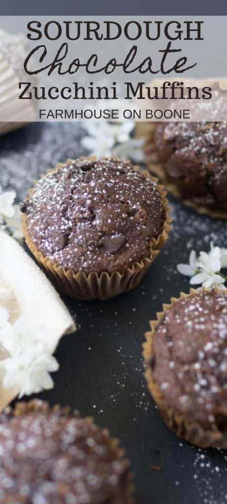 close up of chocolate zucchini muffins on a black countertop with flowers