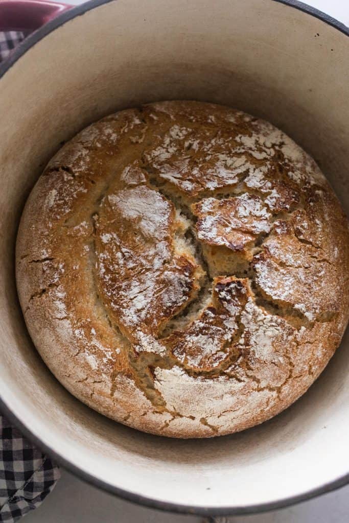 overhead photo of homemade artisan sourdough bread in a dutch oven