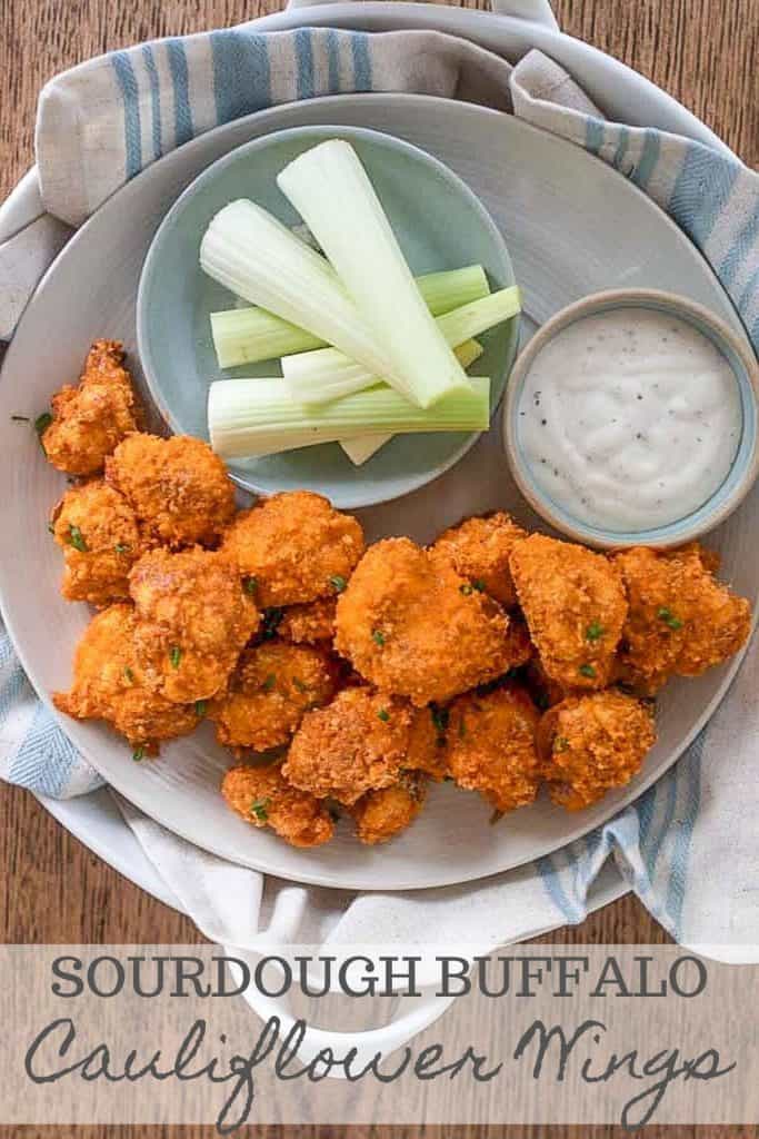 sourdough battered buffalo cauliflower wings on a gray plate with a side of teaser dipping sauce and a bowl full of celery sticks
