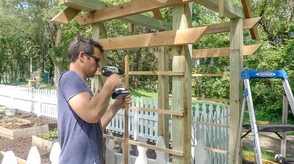 man drilling in a center post to lattice on a arbor