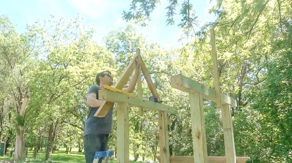 man drilling arbor roof pitch into center post