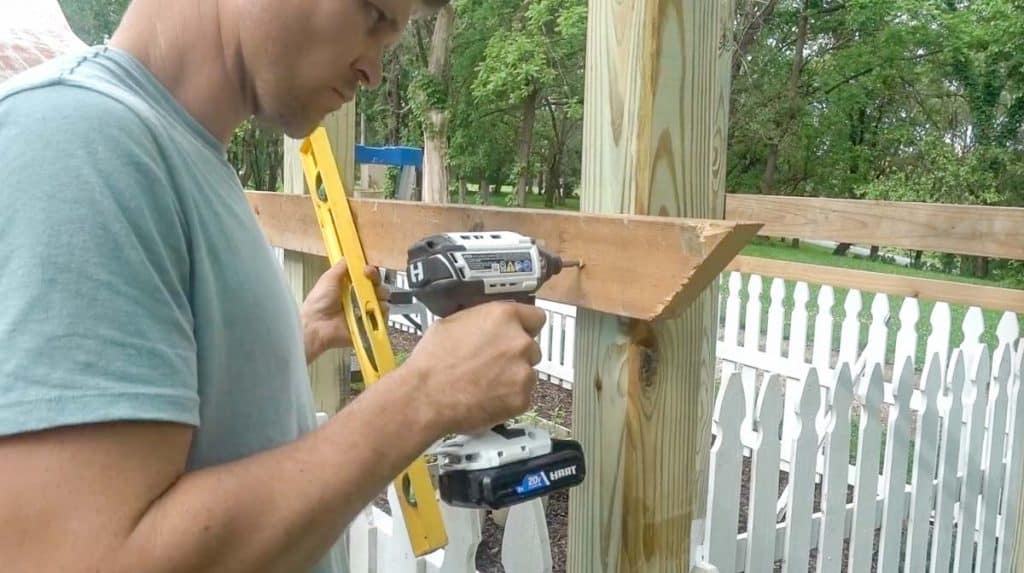 man screwing in a 2x4 into arbor posts