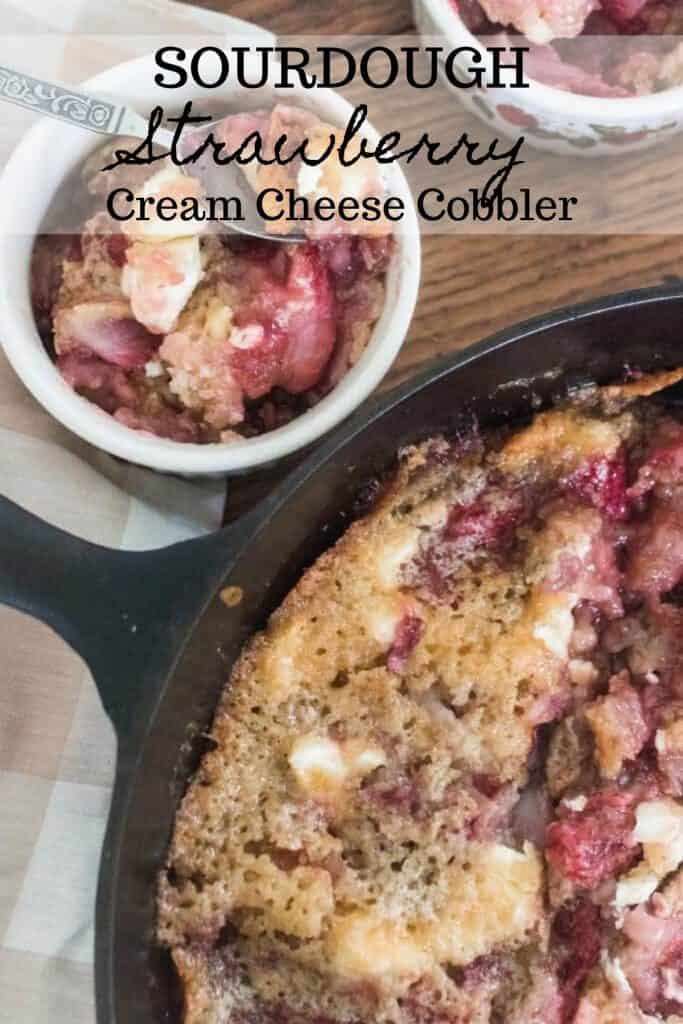 sourdough strawberry cream cheese cobbler in a cast iron skillet with a wooden spoon two ramekins full of cobbler