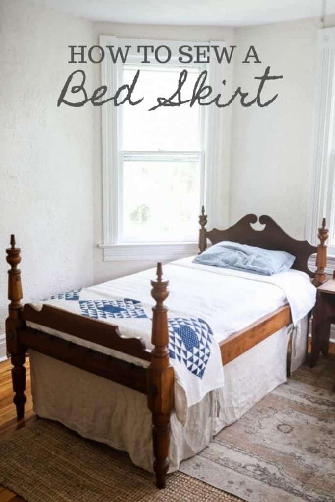 antique wooden bed with a white bedspread, blue and white build near the footboard and a linen bed skirt