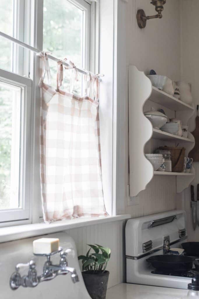 peach and cream linen DIY cafe curtain handing on a kitchen window above an antique farm sink
