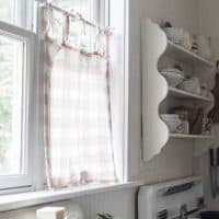 peach and cream linen DIY cafe curtain handing on a kitchen window above an antique farm sink
