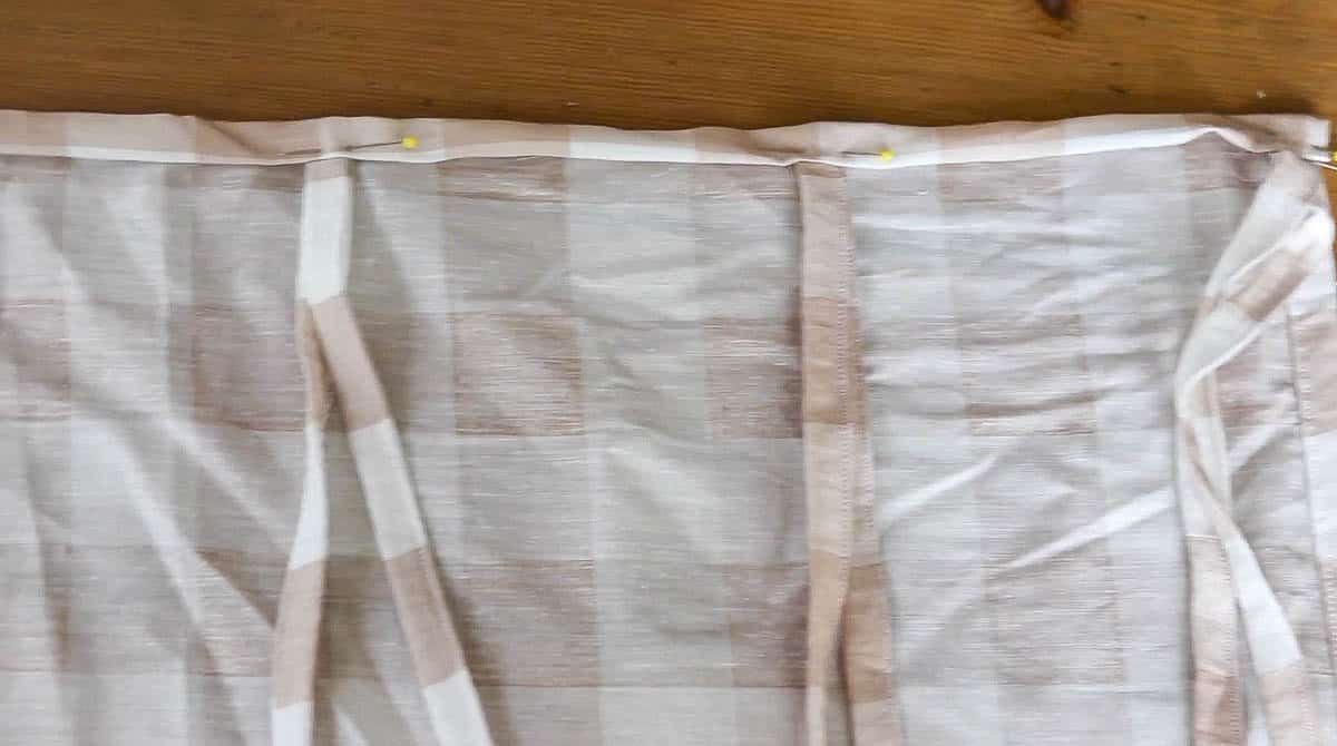 ties being sewn into the top of a curtain panel