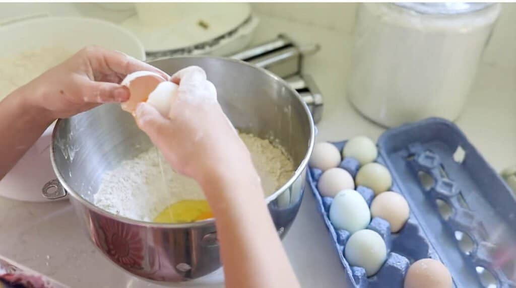 eggs being cracking into a bowl full of flour