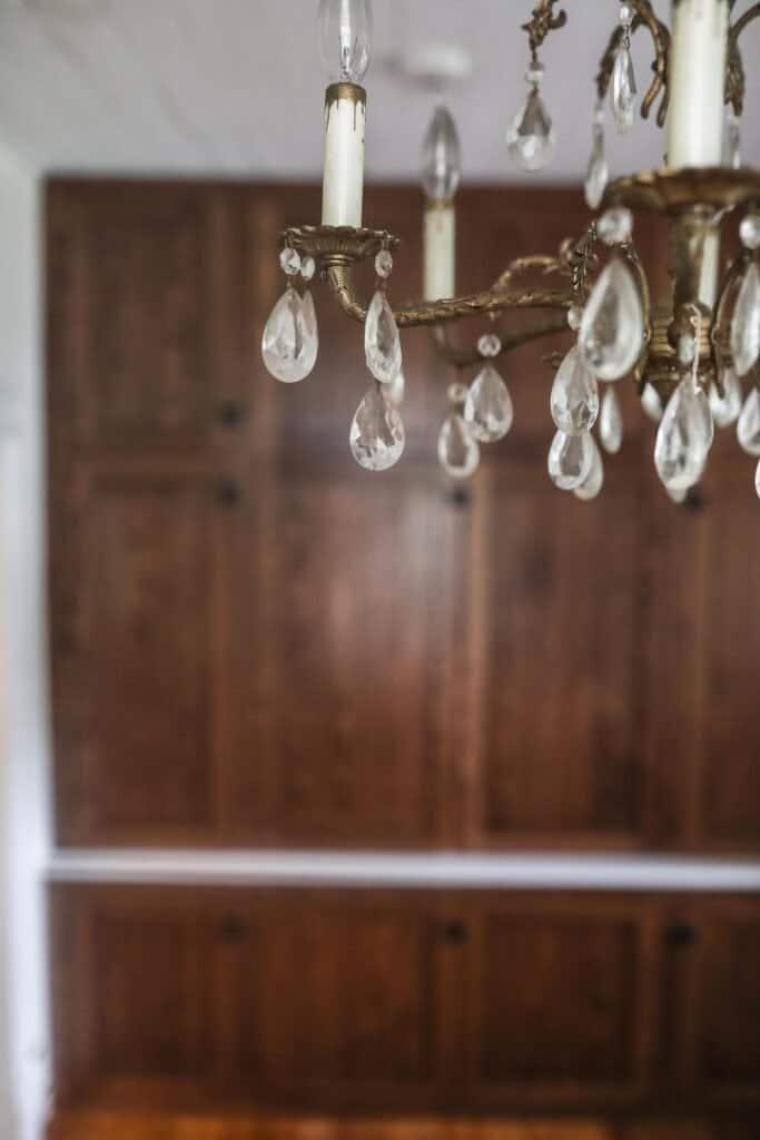 front view of wooden antique inspired cabinetry with a antique chandelier in front