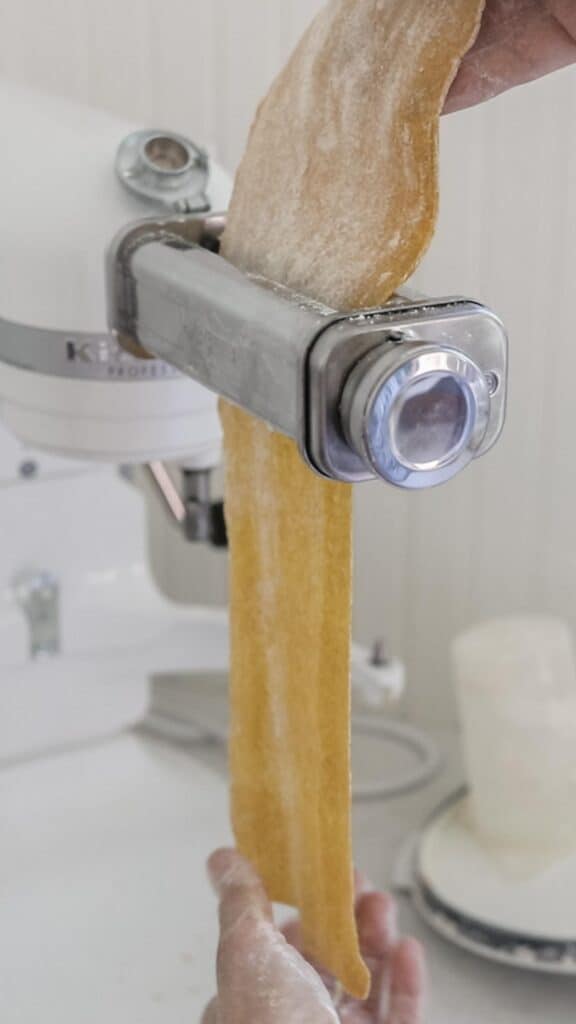 pasta dough being thinned out with a pasta maker