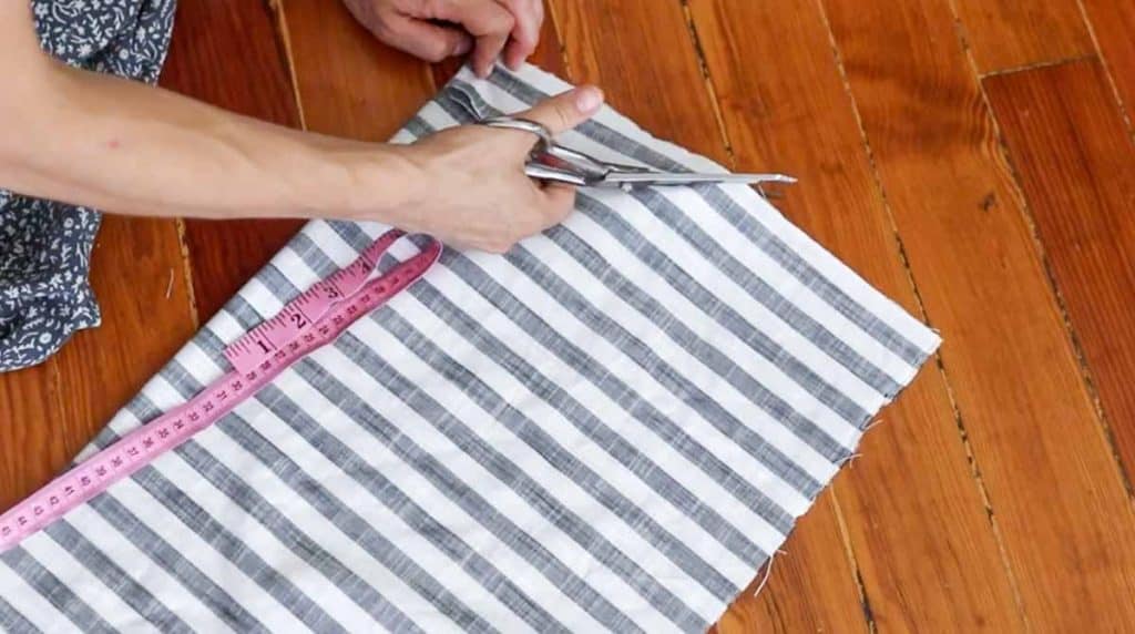 women cutting stripped fabric to create a neckline for a shirt