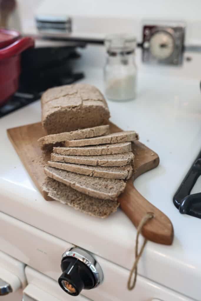 loaf of sourdough rye bread on a wood cutting board on an antique stove