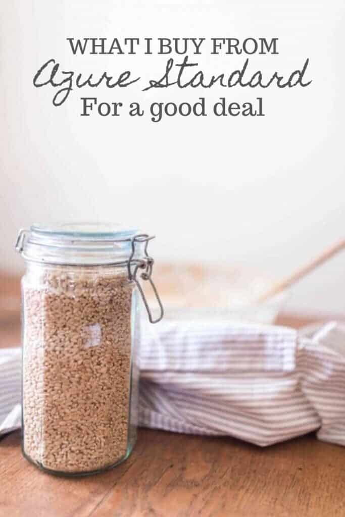 rice in a flip top glass har with a stripped towel in the background and a bowl of sourdough starter and a wooden spoon.