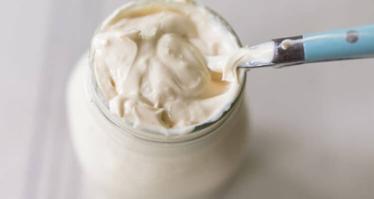 homemade sourdough cream in a mason jar with a spoon in the jar