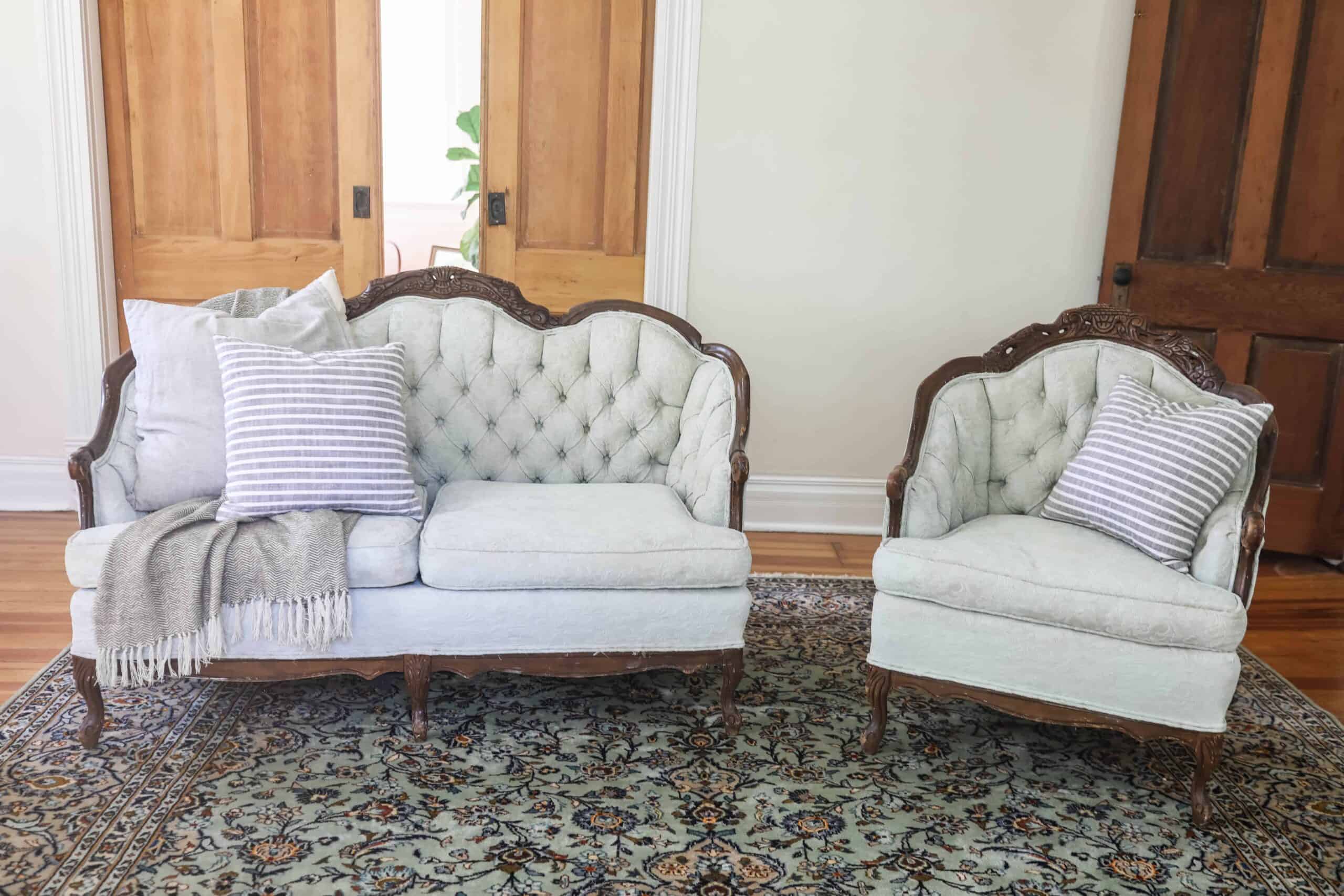a victorian loveseat and chair freshly painted with chalk paint in a soft green color on a rug with pillows and a blanket draped over